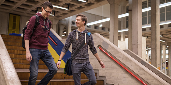 Foto: Zwei Studenten steigen die Treppe in der Halle des Campus Bergedorf herab.
